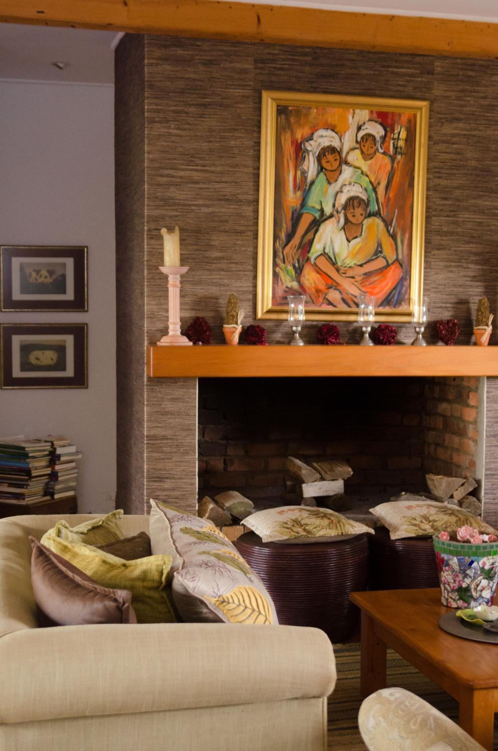Una sala de estar con chimenea, un cuadro sobre ella y una pila de libros en una mesita.