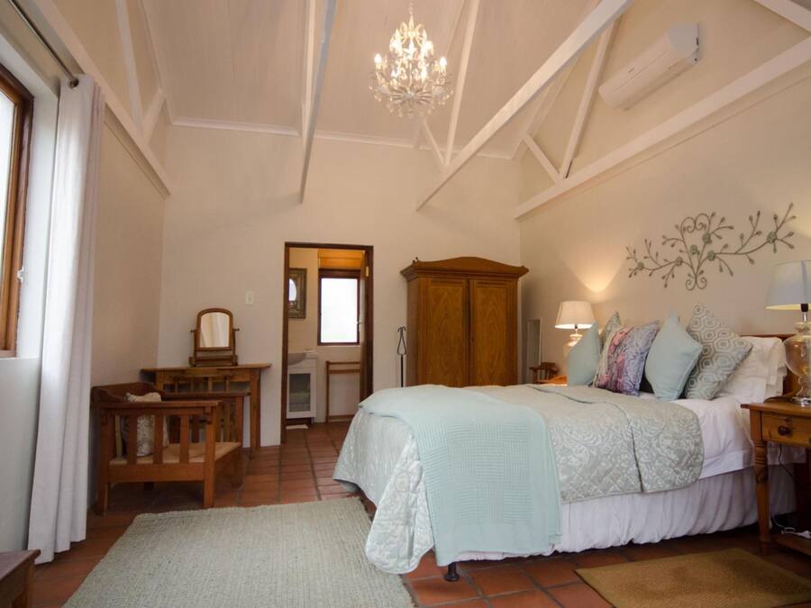 A bedroom with a large bed, a wooden wardrobe, a chandelier, and a wall-mounted lamp.