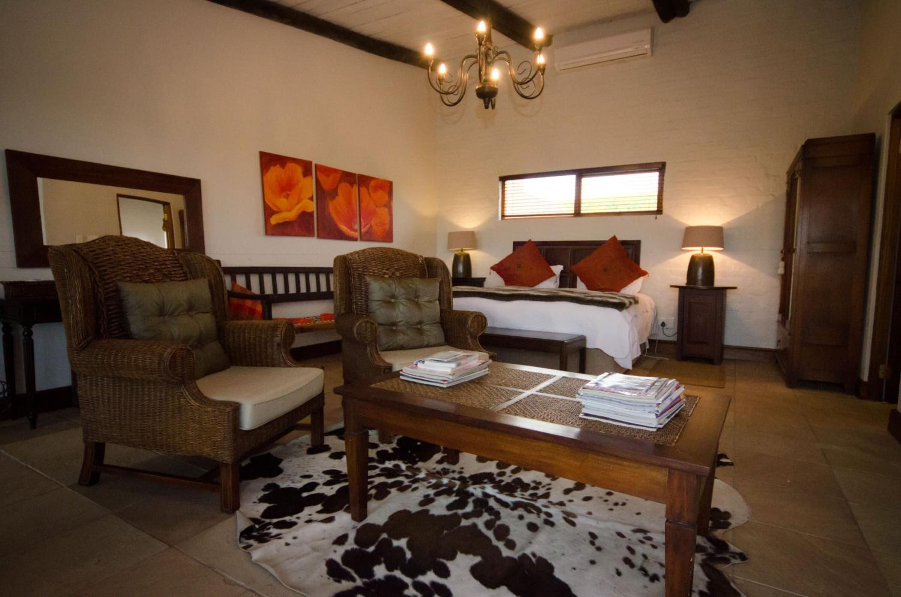 A cozy living room with a sofa, armchairs, a coffee table, and a bed with pillows.