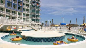 Un área de piscina con varias toboganes de agua y un edificio de varios niveles con balcones.
