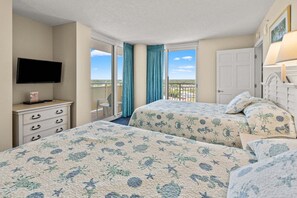 A hotel room with two beds, a TV, a dresser, and a balcony with a view.
