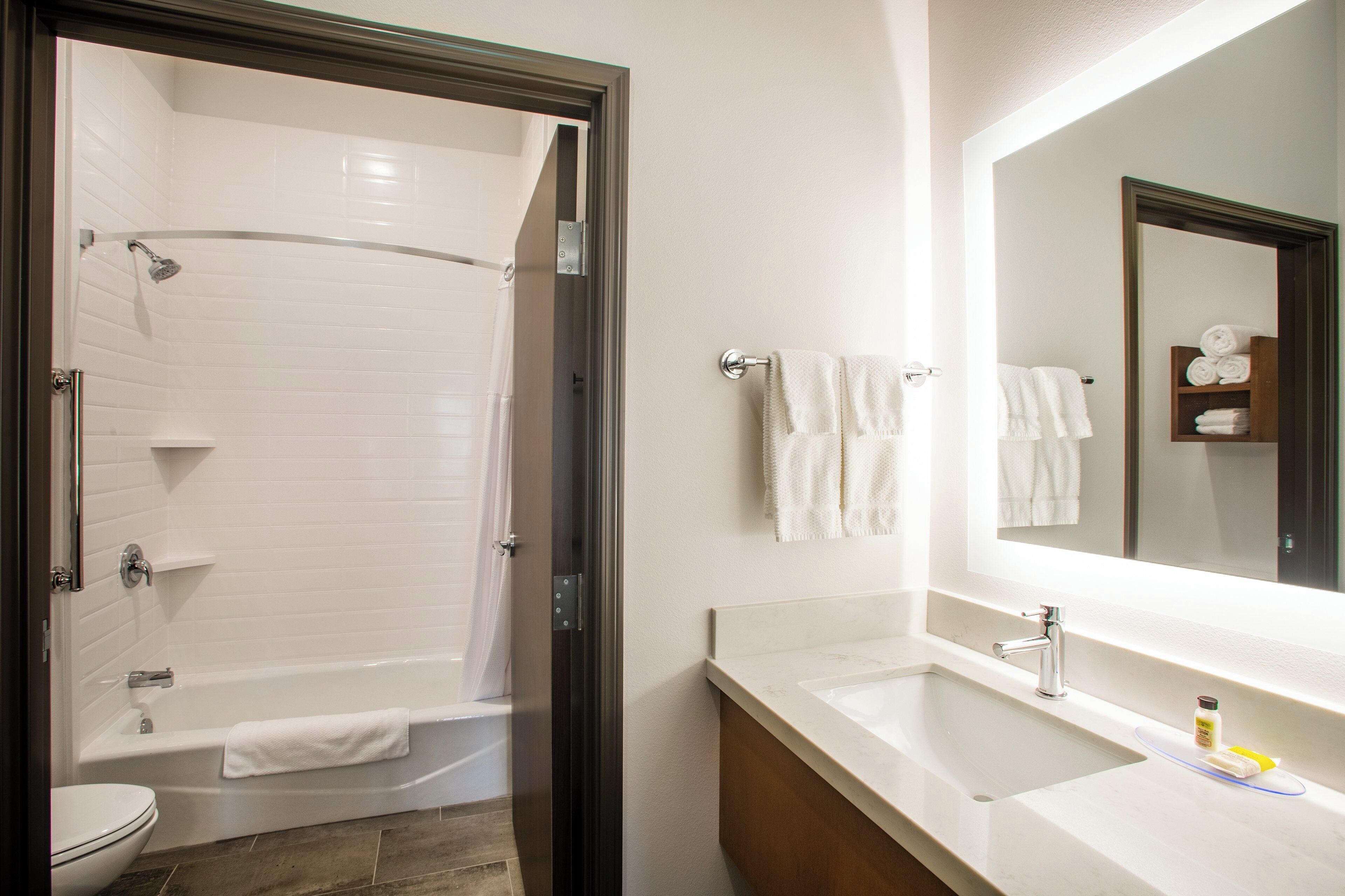 A bathroom with a shower, toilet, sink, and a mirror.