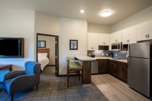 Een kleine hotelkamer met kitchenette, een bed, een televisie en een zithoek.