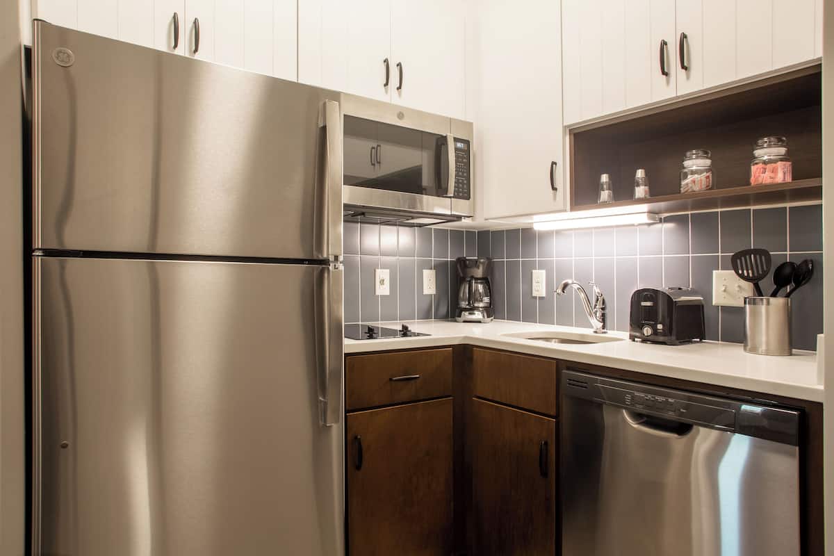 Una cocina moderna con electrodomésticos de acero inoxidable, armarios de madera y un salpicadero de azulejos.