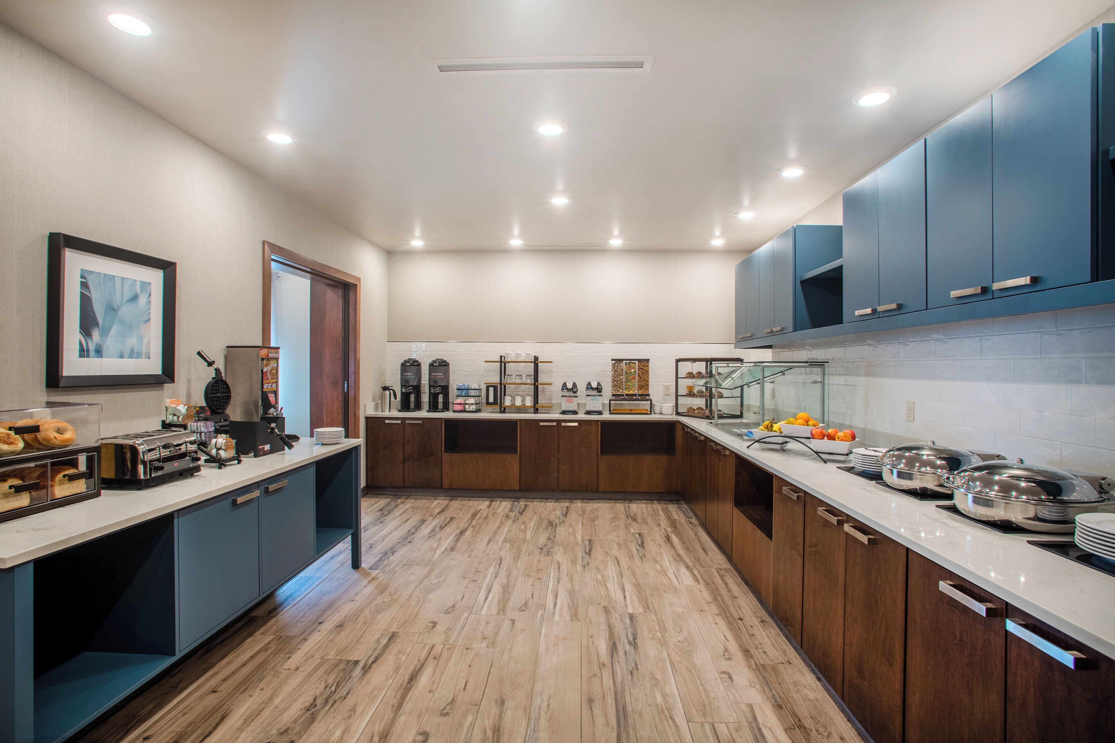 A modern kitchen with wooden cabinets, a marble countertop, and various appliances.