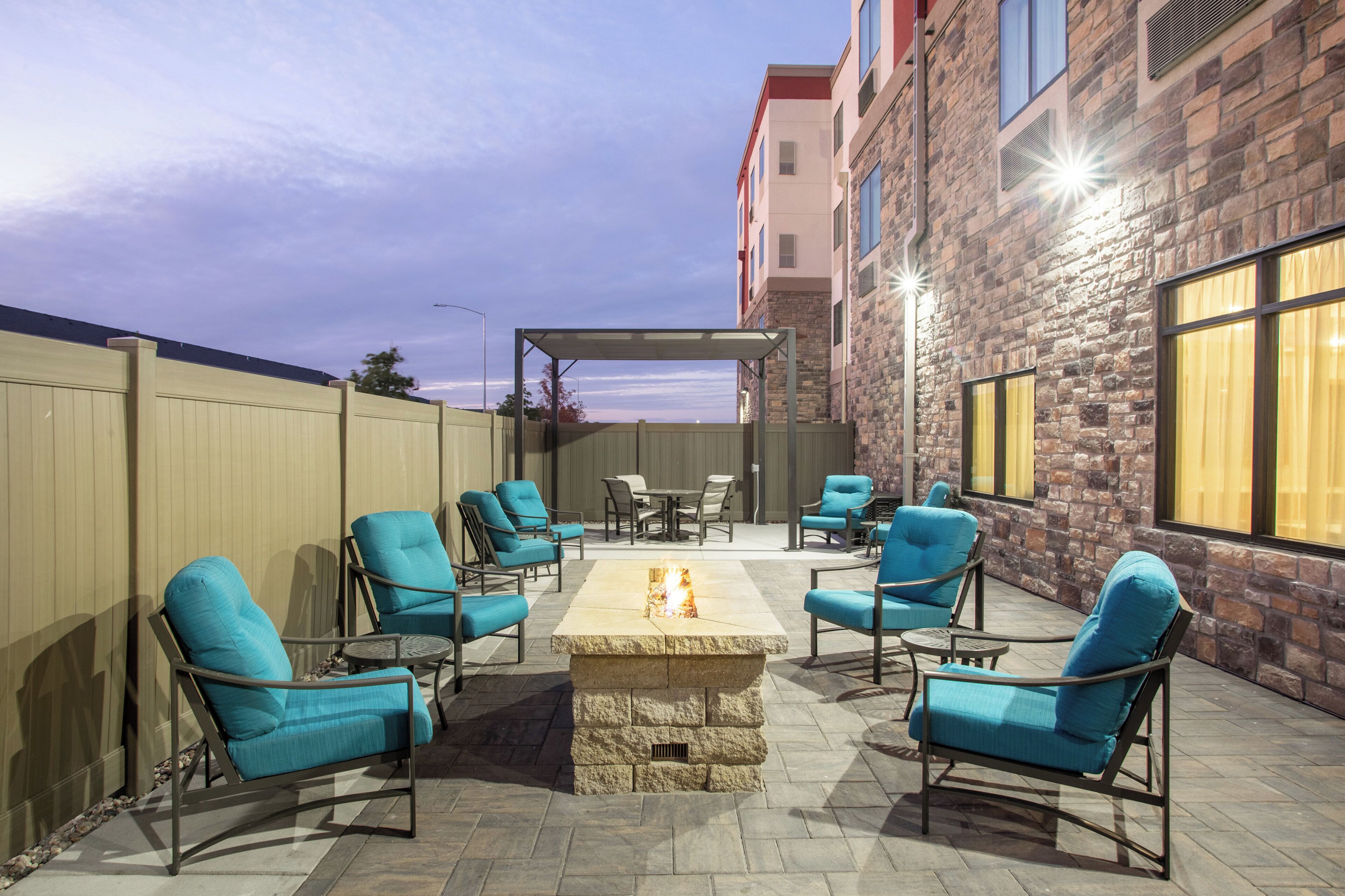 Une terrasse extérieure avec un foyer, des sièges et une vue sur un bâtiment.