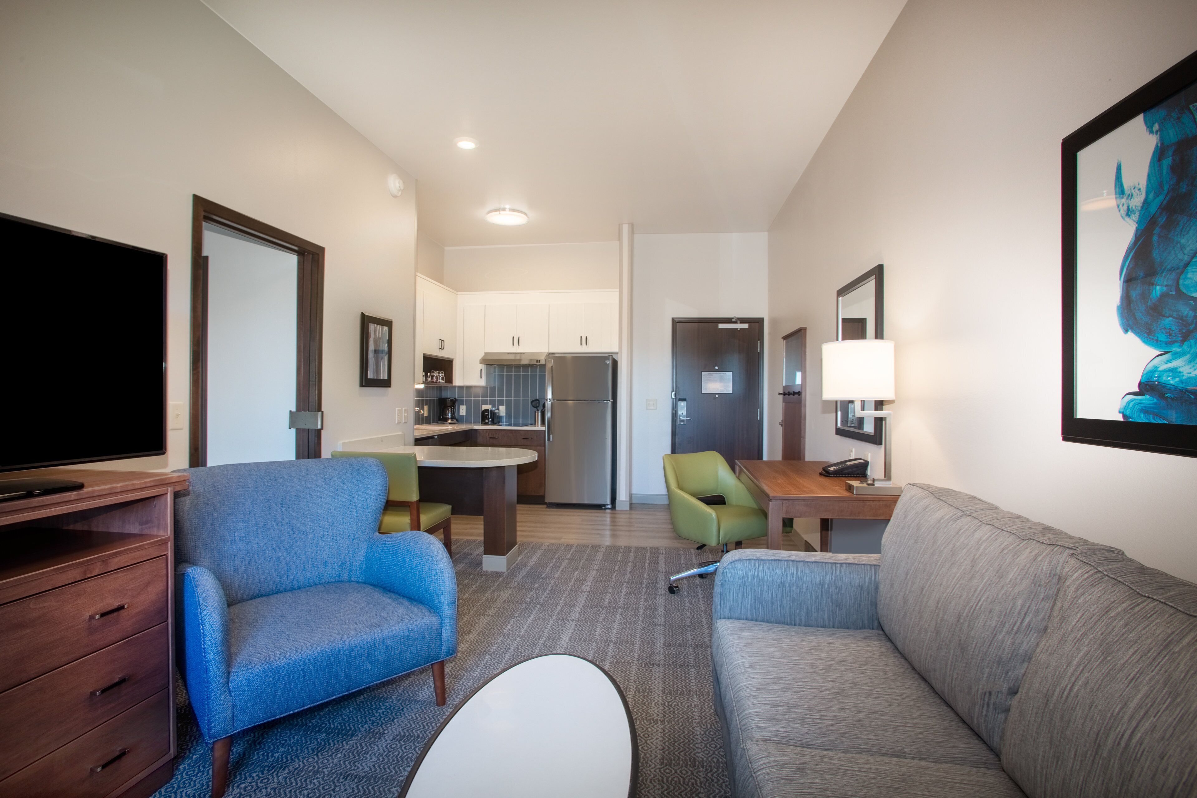 Une chambre d’hôtel compacte comprenant un coin salon, une kitchenette et un téléviseur à écran plat.