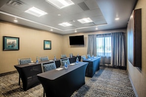 A conference room with a long table, chairs, water bottles, a flat-screen TV, and a window with curtains. - Staybridge Suites Sioux Falls Southwest by IHG (Sioux Falls)