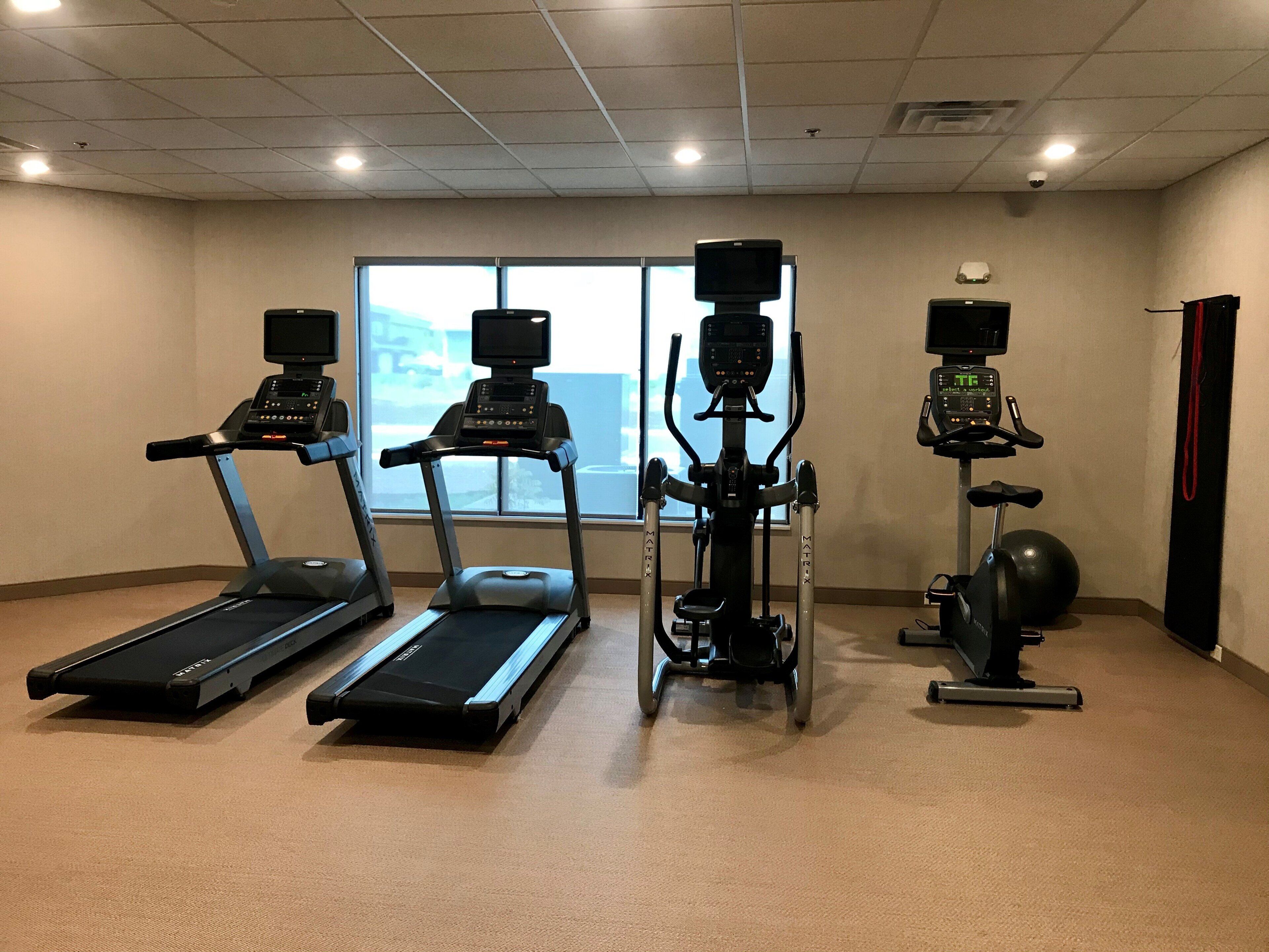 A fitness room with treadmills, an elliptical, and a stationary bike.