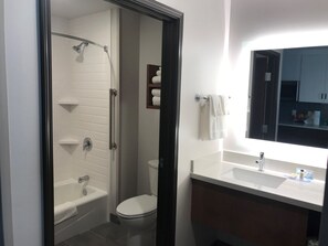 Een badkamer met een bad, toilet en een wastafel met spiegel.