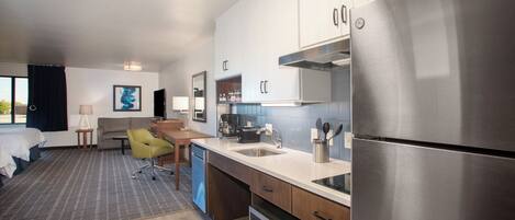 Une chambre d’hôtel moderne équipée d’une kitchenette, d’un lit, d’un canapé et d’un coin repas.