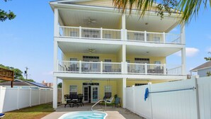 A two-story building with a pool, a balcony on the upper floor, and a fenced backyard. - Charmed home w/private pool, game room, wet bar, covered porches, sun deck, walk to beach (North Myrtle Beach)