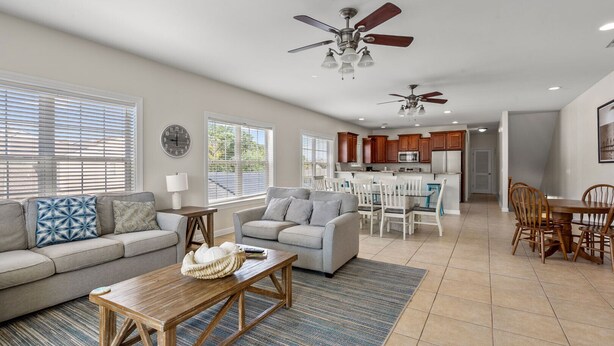 A spacious living room with a sofa, coffee table, and dining area with chairs and a table. There is a kitchen in the background with cabinets and a microwave. - Charmed home w/private pool, game room, wet bar, covered porches, sun deck, walk to beach (North Myrtle Beach)