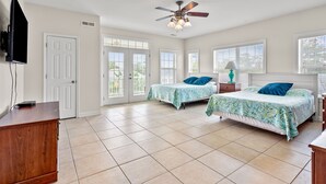 A spacious bedroom with two beds, a ceiling fan, and large windows. - Charmed home w/private pool, game room, wet bar, covered porches, sun deck, walk to beach (North Myrtle Beach)
