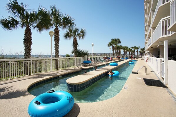 A pool area with multiple lanes, lounge chairs, and palm trees.