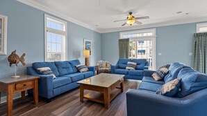 A living room with blue sofas, a wooden coffee table, and a ceiling fan.