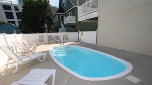 Piscina con sillas de descanso blancas y una zona cubierta.