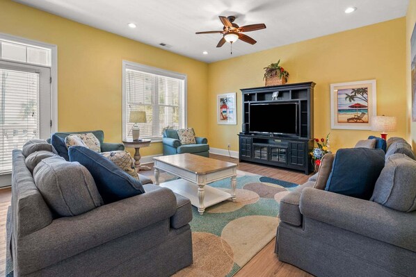 A living room with two sofas, a coffee table, a TV, and a ceiling fan.