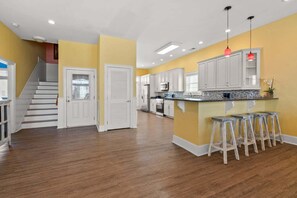 A spacious kitchen with a central island, white cabinetry, and a wooden floor.