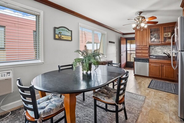 A dining area with a round table, chairs, and a potted plant. - Best panoramic views in NMB! Views of inlet, across street from beach, pool, tennis, fish, surf (North Myrtle Beach)