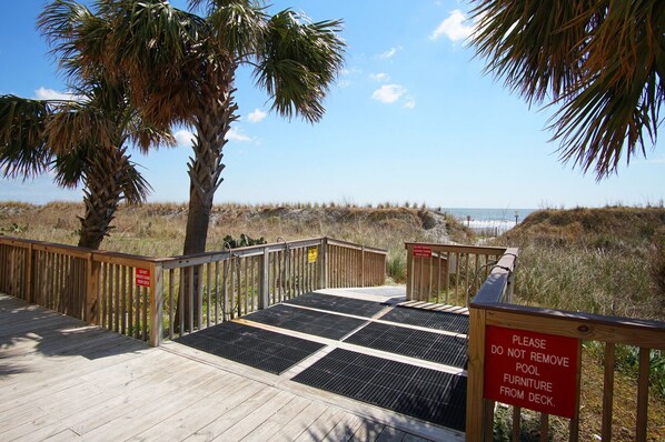 A wooden deck with a warning sign about not removing lounge chairs from the deck. - Condo with great ocean view, large balcony w/pool & hot tub in popular Cherry Grove Beach (North Myrtle Beach)