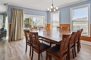 A dining room with a large wooden table, six chairs, and a chandelier. - Large villa just steps to the beach w/private pool, game room & elevator-perfect family rental (North Myrtle Beach)