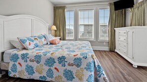 A bedroom with a bed, a nightstand, a dresser, a ceiling fan, and a window with curtains. - Large villa just steps to the beach w/private pool, game room & elevator-perfect family rental (North Myrtle Beach)