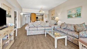 A living room with a sofa set, a coffee table, and a TV on a wooden stand.