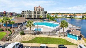 A hotel with a large swimming pool, a dock, and a view of a lake.