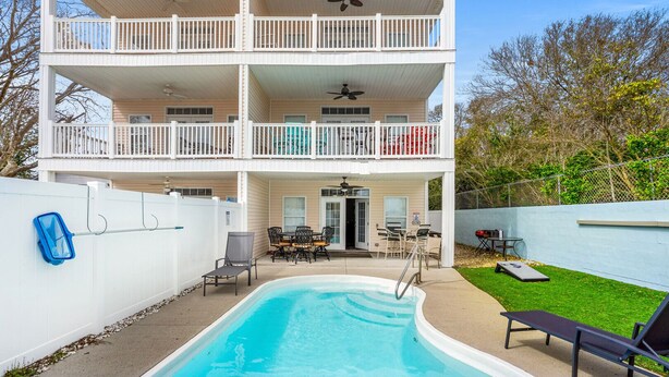A two-story building with a swimming pool, outdoor seating, and a fenced yard. - Beautiful villa w/private pool, hot tub & game room-grill & picnic table-in North Myrtle Beach (North Myrtle Beach)