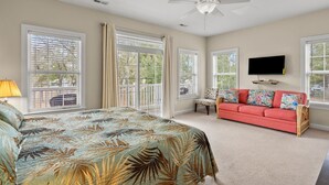 A bedroom with a large bed, a red sofa, and a TV mounted on the wall. - Beautiful villa w/private pool, hot tub & game room-grill & picnic table-in North Myrtle Beach (North Myrtle Beach)