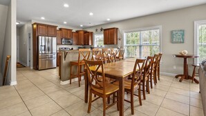A spacious kitchen with wooden cabinets, a stainless steel refrigerator, and a large dining table surrounded by chairs. - Beautiful villa w/private pool, hot tub & game room-grill & picnic table-in North Myrtle Beach (North Myrtle Beach)