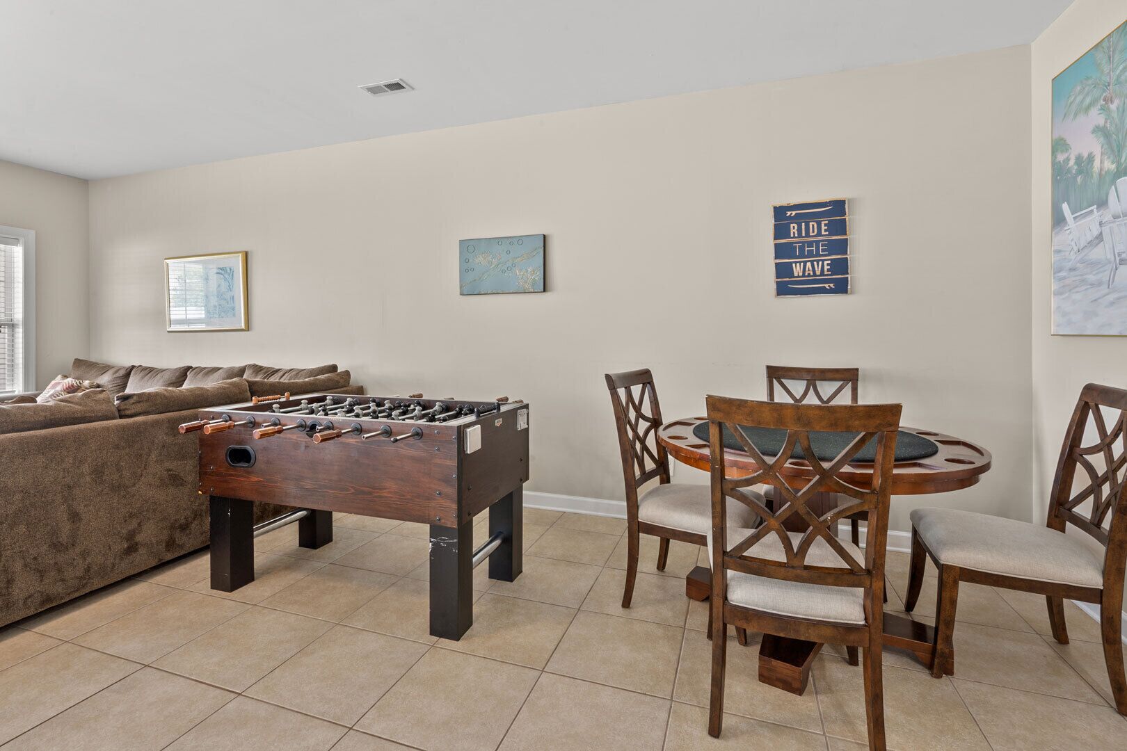 A living room with a foosball table, a sofa, and a dining area with chairs and a table.