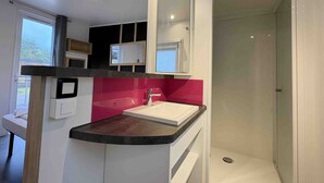 A modern bathroom with a vanity, a mirror, a shower, and a window.