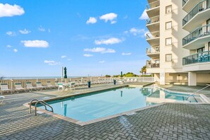 A swimming pool with lounge chairs and a view of the ocean.
