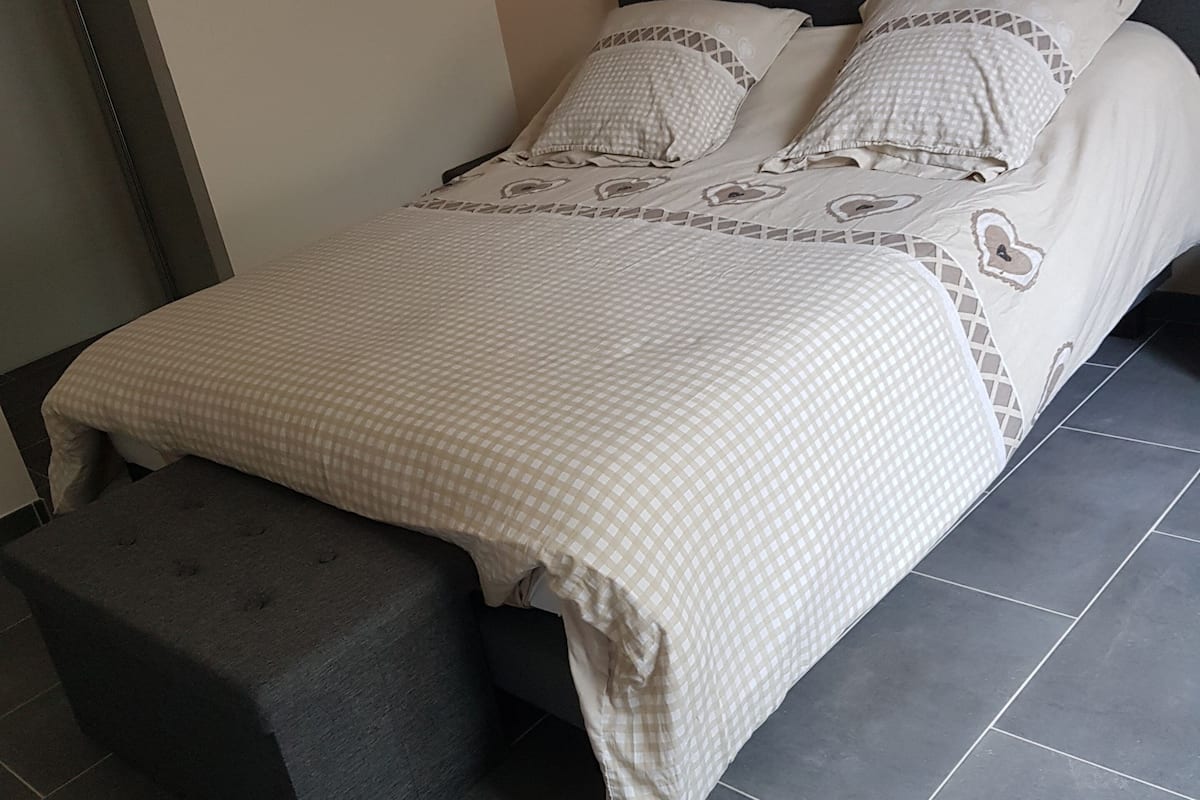Ein Bett mit karierter Bettdecke, zwei Kissen und einer passenden Bank.