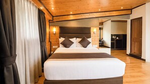 A hotel room with a large bed, wooden ceiling, and a view into the kitchen area. - Sumitel Shangrila (Gangtok)