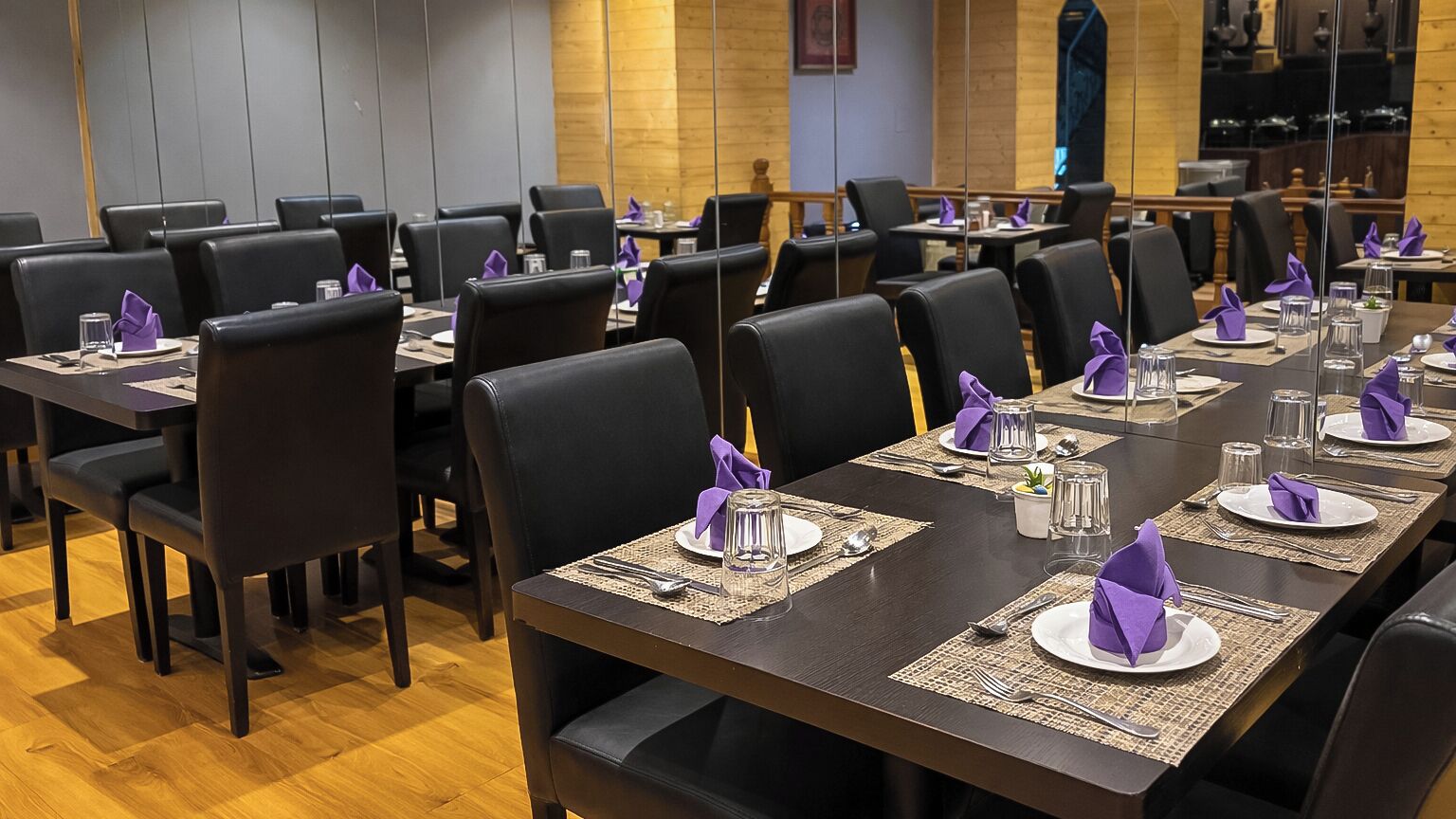 A conference room with multiple tables, each set with plates, cutlery, and purple napkins.