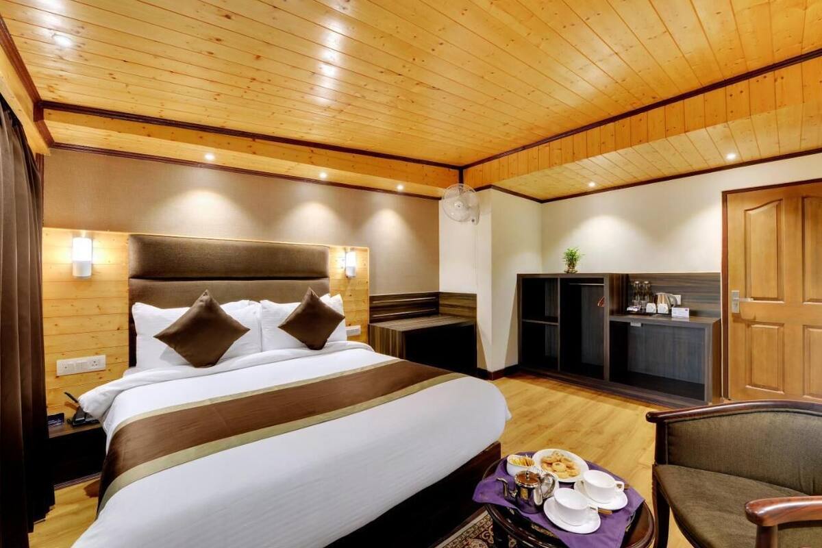 A hotel room with a large bed, a desk, and a dining area with a tray of breakfast.