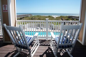A balcony with a pool, white chairs, and a view of the ocean. - Spacious condo steps to the beach w/fitness center, indoor and outdoor pools, hot tub (North Myrtle Beach)