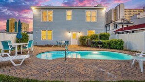 Ein zweistöckiges Haus mit Swimmingpool, Terrassenmöbeln und einem gepflegten Garten.