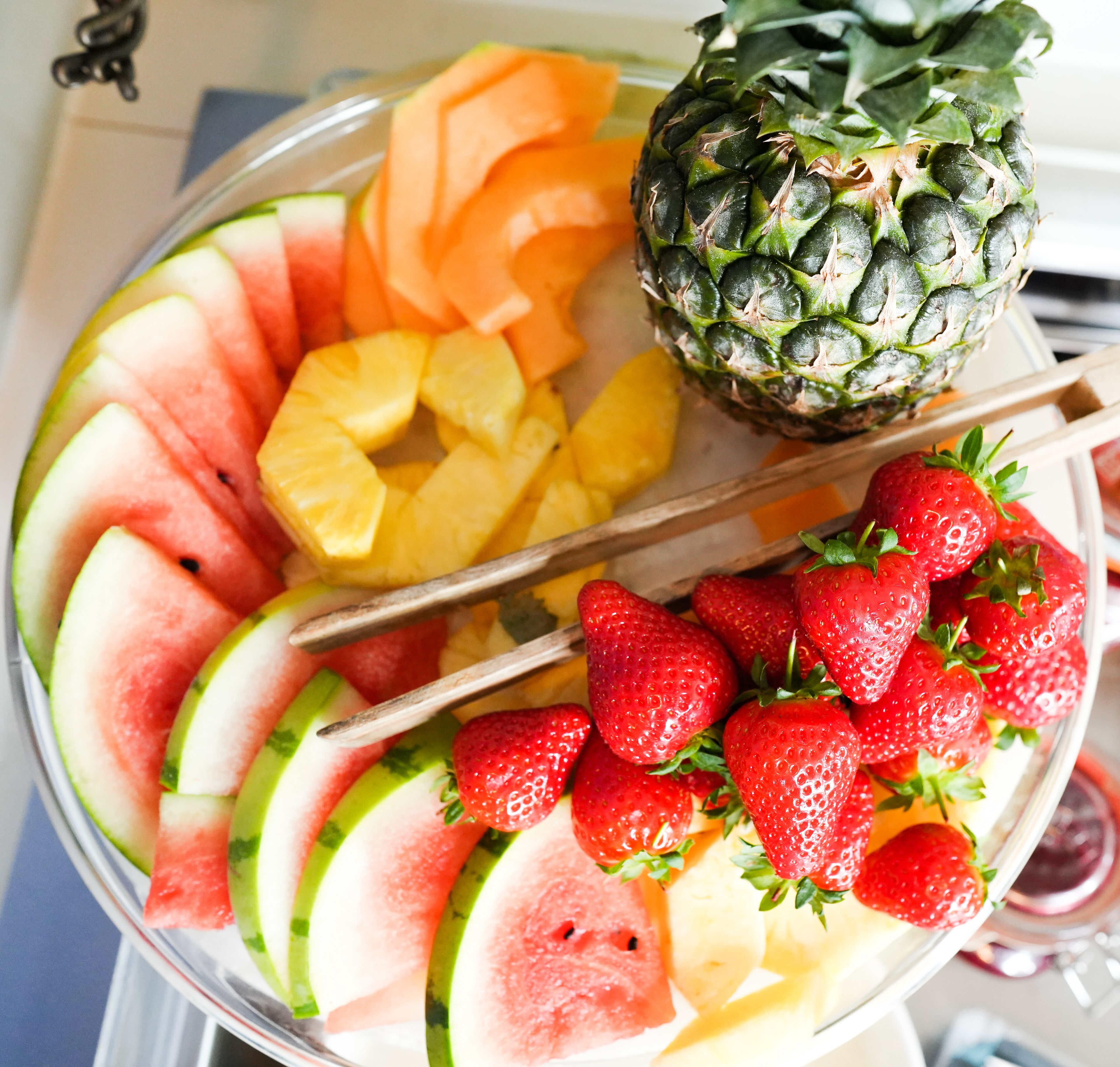 A fruit platter with watermelon, pineapple, cantaloupe, strawberries, and a pineapple.
