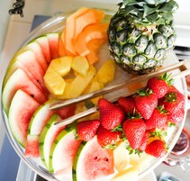 Una bandeja de frutas con sandía, piña, melón cantalupo, fresas y una piña.