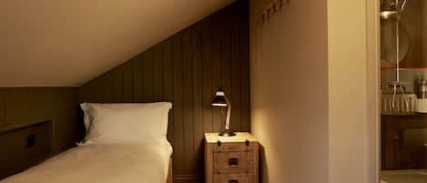 Ein Schlafzimmer mit einem Bett, einem Nachttisch mit Lampe, einer Kommode und einer Duschkabine.