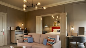 A hotel room with a sofa, a desk, a chair, and a bed.