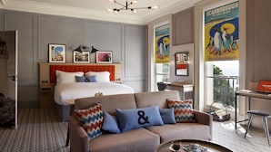 A hotel room with a bed, a sofa, a desk, and a large window.