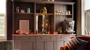 A kitchen with a coffee machine, shelves with jars, and a chessboard.