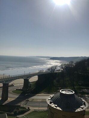 Vista costera con un puente, playa y un edificio circular con cúpula.