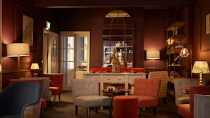 A warmly lit lounge area with multiple seating options, a chess table, and a decorative statue.