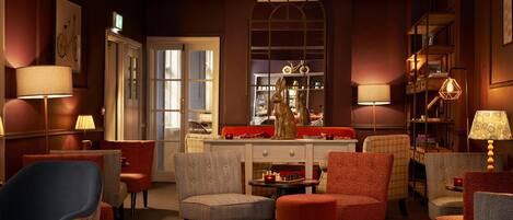 A warmly lit lounge area with multiple seating options, a chess table, and a decorative statue.